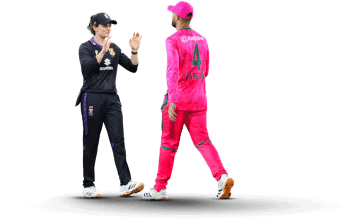 Two cricketers in contrasting uniforms exchange a congratulatory gesture on a dark background; one in black, the other in bright pink with the number 4 on his back.